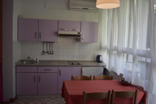 a kitchen with purple cabinets and a table with chairs at Podgora Apartmani Sonja in Podgora