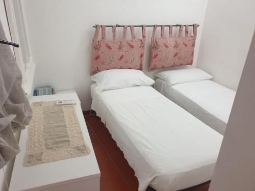 2 Betten in einem kleinen Zimmer mit einem Tisch in der Unterkunft Casa Ciccio in Terrasini