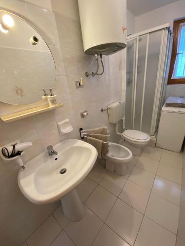 a white bathroom with a sink and a toilet at Residenza Capinera in Bormio
