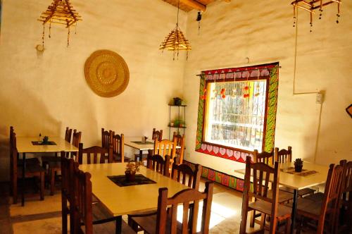 uma sala de jantar com mesas e cadeiras e uma janela em Giramundo Hostel Purmamarca em Purmamarca