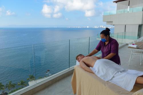 a woman giving a man a massage on a balcony at Maxwell Residences at Indah in Puerto Vallarta
