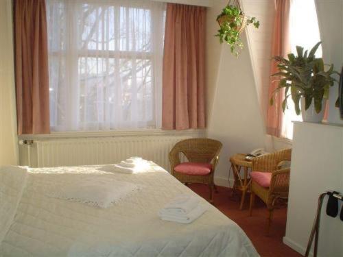 a bedroom with a bed and a window and chairs at Staten Hotel in The Hague