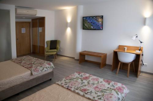 a hotel room with a bed and a desk and a chair at Hotel Marisol in Macedo de Cavaleiros