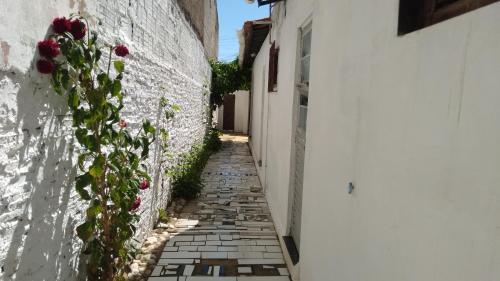 a narrow alley with roses on the side of a building at Paracuru HolaOnda WaveHostel in Paracuru