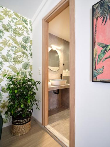a bathroom with a mirror and a sink and a plant at The Tree Suites in Skiathos