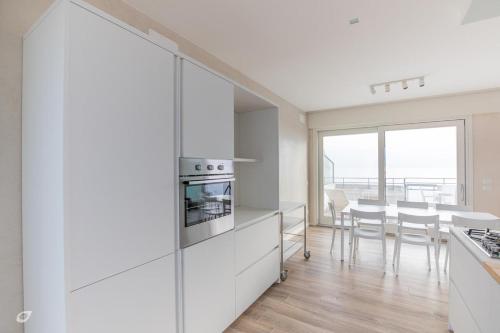 a kitchen with white cabinets and a table with chairs at Beachfront Penthouse with private parking in Camaiore