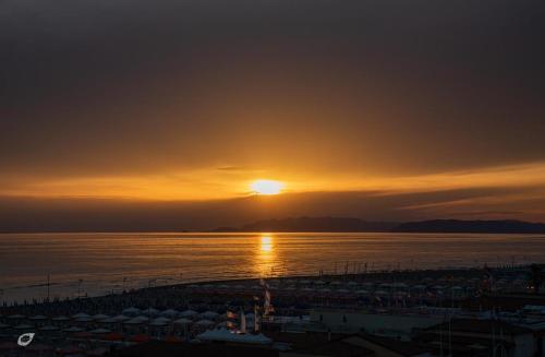 a sunset over a body of water with a pier at Beachfront Penthouse with private parking in Camaiore