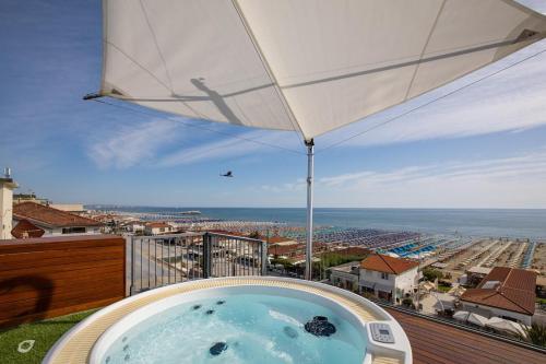 a hot tub on a balcony with an umbrella at Beachfront Penthouse with private parking in Camaiore