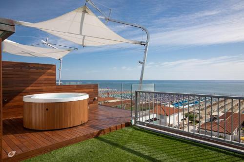 a balcony with a hot tub and an umbrella at Beachfront Penthouse with private parking in Camaiore