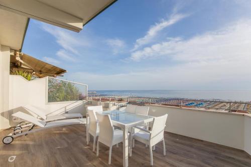 a balcony with a table and chairs and a view of the ocean at Beachfront Penthouse with private parking in Camaiore