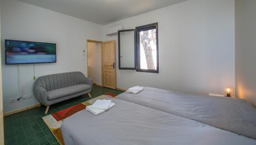 a bedroom with a large bed and a chair at MAS de COLOMINA Aigues-Mortes in Aigues-Mortes