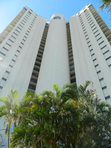 two tall white buildings with palm trees in the foreground at Royal Palm Resort on the Beach in Gold Coast