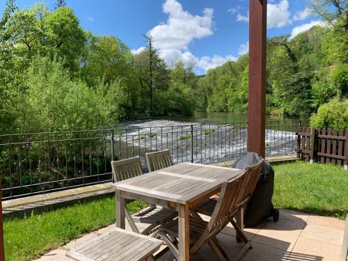 a wooden table and two chairs on a deck with a river at Auf der Zschopau-Insel in Zschopau