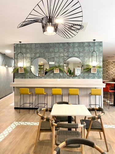 a restaurant with yellow chairs and a counter with mirrors at Soho Boutique Córdoba in Córdoba