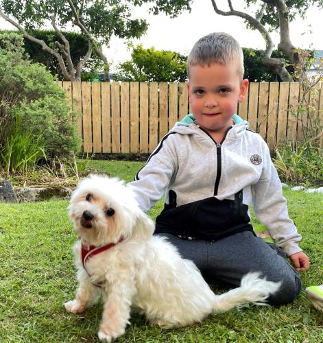 a young boy sitting next to a small white dog at Atlantic Apartotel in Bundoran