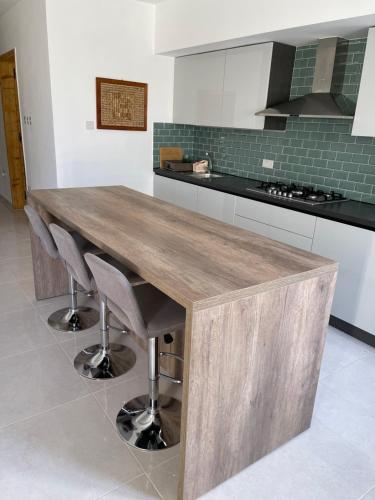 a kitchen with a wooden table and some chairs at Sunset Modern Apt near the beach in Birżebbuġa