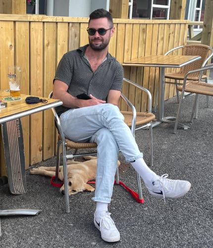 a man sitting in a chair next to a dog at Atlantic Apartotel in Bundoran