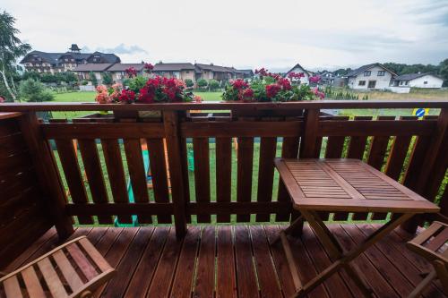 a wooden bench sitting on a deck with flowers at Penzion Rysy in Veľká Lomnica