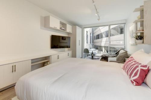 a white bedroom with a large white bed and a window at Placemakr Dupont Circle in Washington