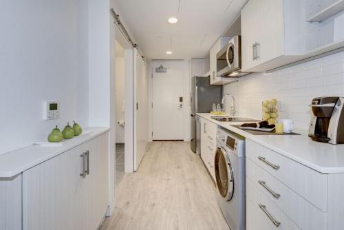 a kitchen with white cabinets and a washer at Placemakr Dupont Circle in Washington