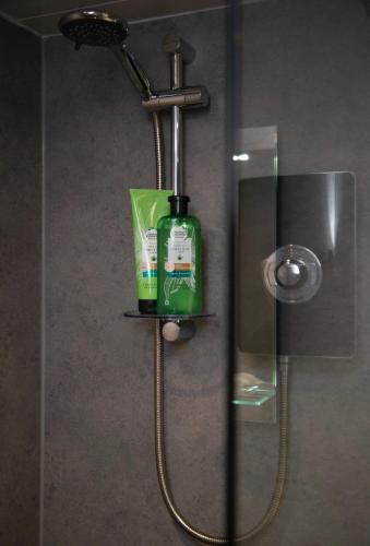 a shower with a green bottle of soap and a shower head at Georgian House in Edinburgh