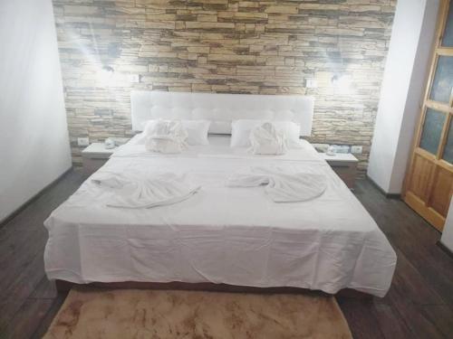 un grande letto bianco con lenzuola e cuscini bianchi di Insomnia Studio a Drobeta-Turnu Severin