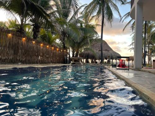 a pool at a resort with palm trees at älanacasadeplaya in San Bernardo del Viento