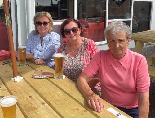 three women sitting at a table withints of beer at Atlantic Apartotel in Bundoran