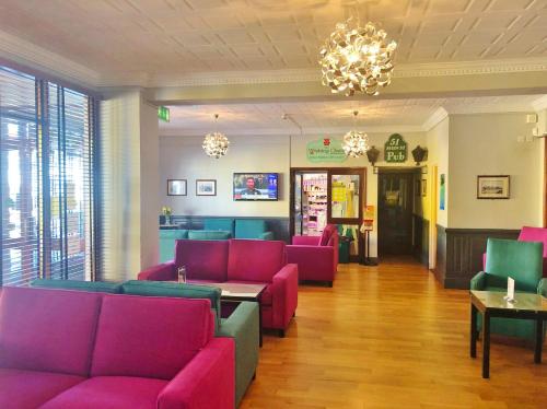a waiting room with pink furniture and a chandelier at Atlantic Apartotel in Bundoran