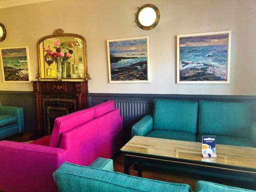 a restaurant with pink and blue chairs and a table at Atlantic Apartotel in Bundoran