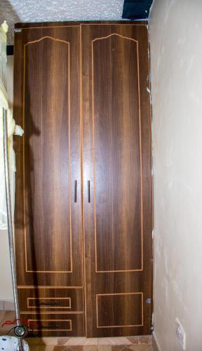 a wooden cabinet in the corner of a room at One Bedroom Furnished in Kasarani-Nairobi in Nairobi
