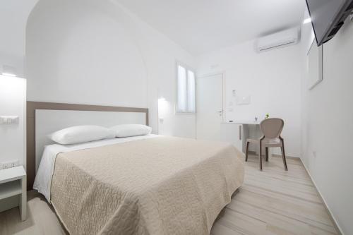 a white bedroom with a bed and a desk at B&B SOLE in Torre San Giovanni Ugento
