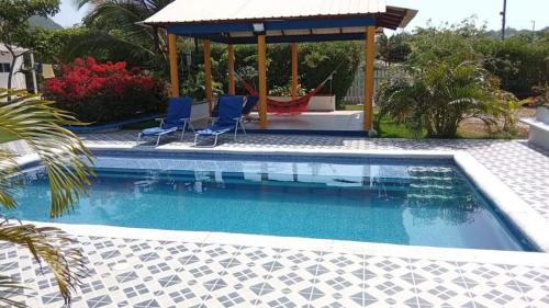 a swimming pool with two chairs and a gazebo at Casa de Campo Palmarito in Tubará