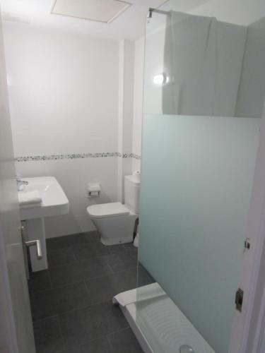 Baño blanco con aseo y lavamanos en Hotel Gesòria Porta Ferrada en Sant Feliu de Guixols