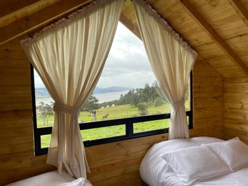 a bedroom with a window with a view of a field at Altozano Cabañas in Guatavita