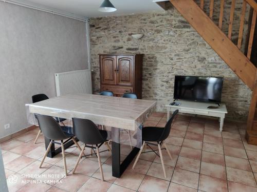 ein Esszimmer mit einem Tisch und Stühlen sowie einem TV in der Unterkunft les gites de la bouldoire Renaissance in Rignac