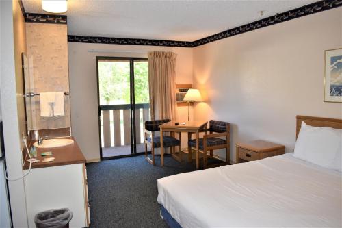 Habitación de hotel con cama, escritorio y ventana en Winthrop Inn, en Winthrop