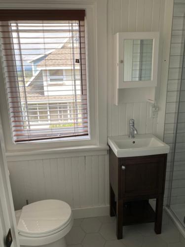 baño con aseo y lavabo y ventana en La Maison entre Mer Montagnes en Cap-Chat