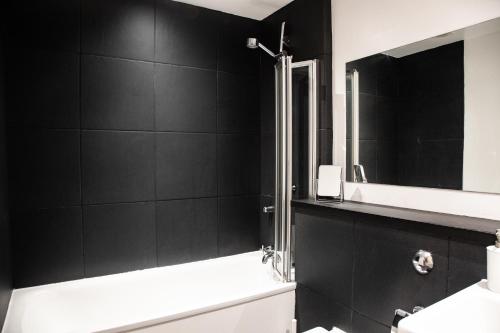 a bathroom with black walls and a sink and a shower at Modern Merchant City Apartment by George Square in Glasgow