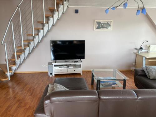 a living room with a couch and a flat screen tv at Moderne Maisonette-Wohnung am Karpfenteich; modern Apartment with view of the carp pond in Barmstedt