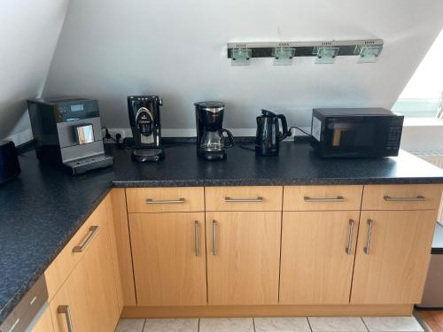a kitchen with a counter top with a microwave and appliances at Moderne Maisonette-Wohnung am Karpfenteich; modern Apartment with view of the carp pond in Barmstedt