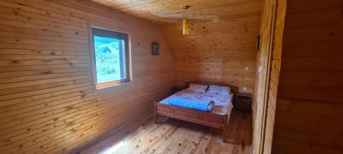 um pequeno quarto com uma cama num chalé de madeira em Guest house STAŠA,Žabljak em Žabljak