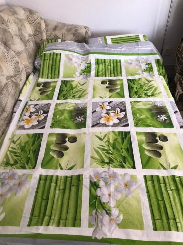 a bed with a quilt with flowers on it at Sea & BBQ apartment , 2nd floor in Liepāja