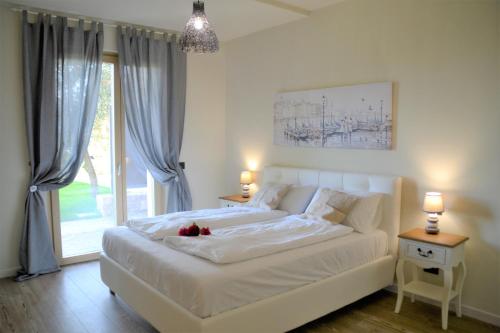 um quarto com uma cama branca e uma grande janela em "Villa Giulia Nicole" Apartaments- Country House em Malcesine