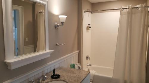 a bathroom with a sink and a shower with a mirror at Eagle Cottages at Gulf State Park in Gulf Shores