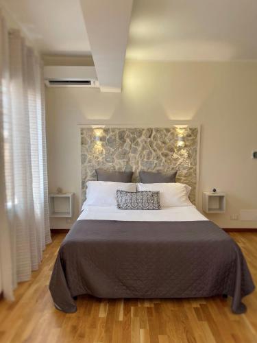a bedroom with a large bed with a stone wall at Domus Cuseni in Taormina