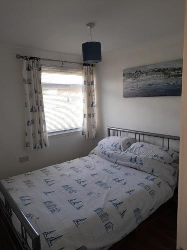 a bedroom with a bed with a comforter and a window at Sunrise 77 Sandown Bay Holiday Centre Generous Ferry Saving! in Sandown