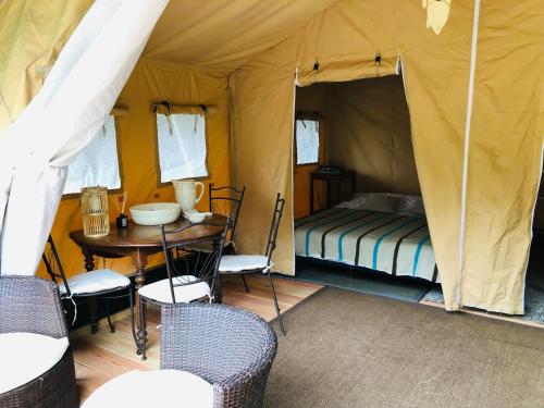 une tente avec une table et un lit. dans l'établissement Tente lodge Élevage Girbal, à La Chapelotte