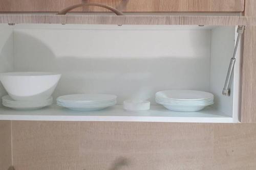 a shelf with white bowls and plates on it at Luxury apartment at Jardin Carthage Tunis in Tunis