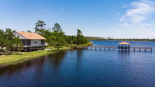 a house on the shore of a lake with a dock at Eagle Cottages at Gulf State Park in Gulf Shores